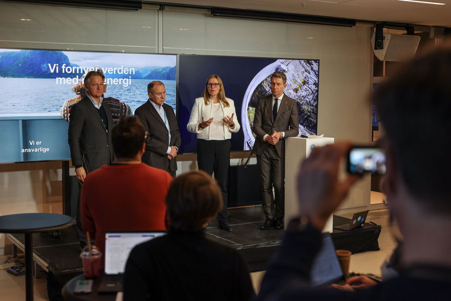 Four people standing on a podium at a press conference