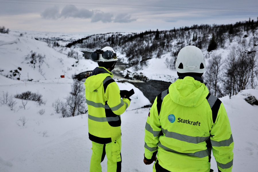 Two colleagues wearing safety gear on top of a hill above the Nesjø dam