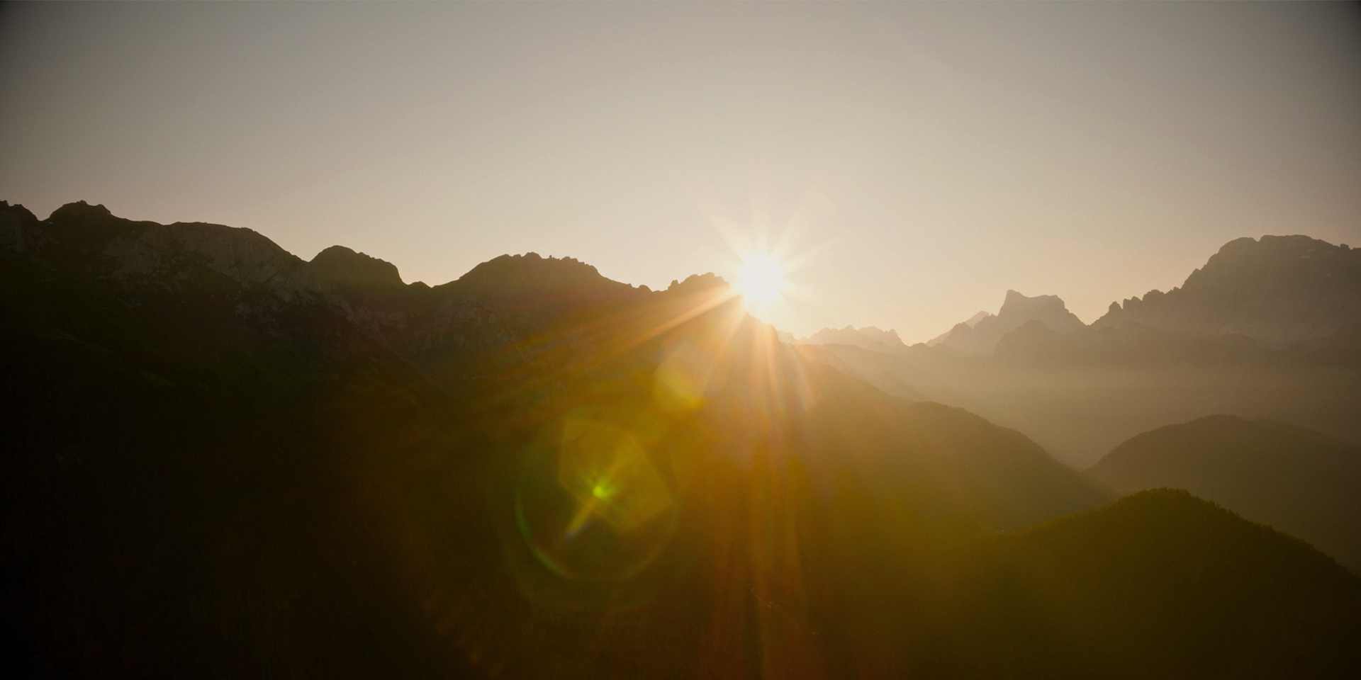 Sun peaking out from behind mountains