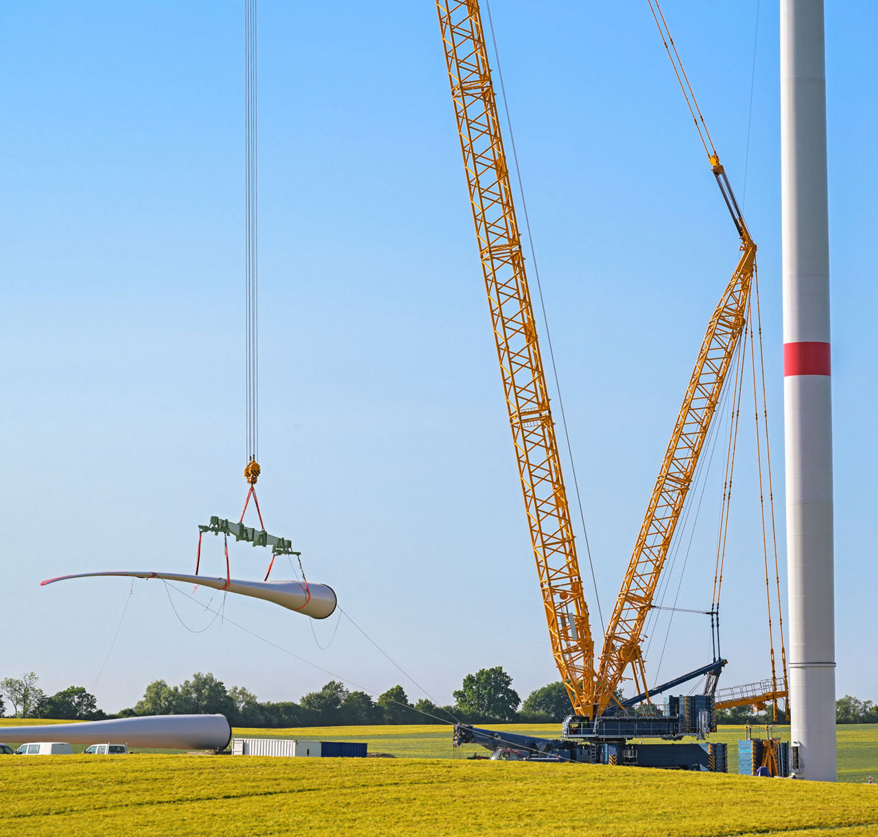 The rotor blade of a wind turbine is hoisted up with a crane.